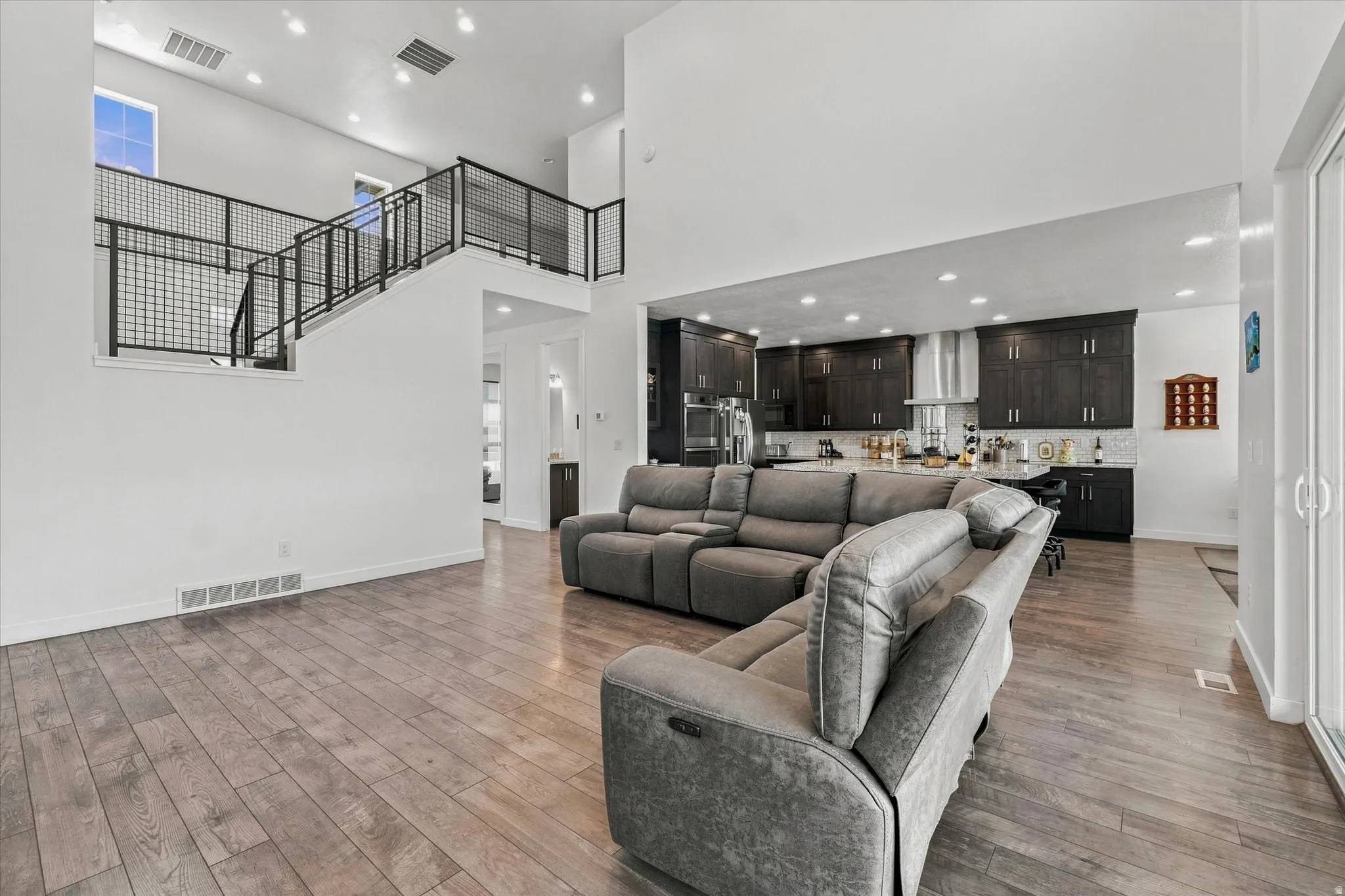 Open-concept living space featuring high ceilings, wood-finish flooring, and a contemporary staircase with metal railings