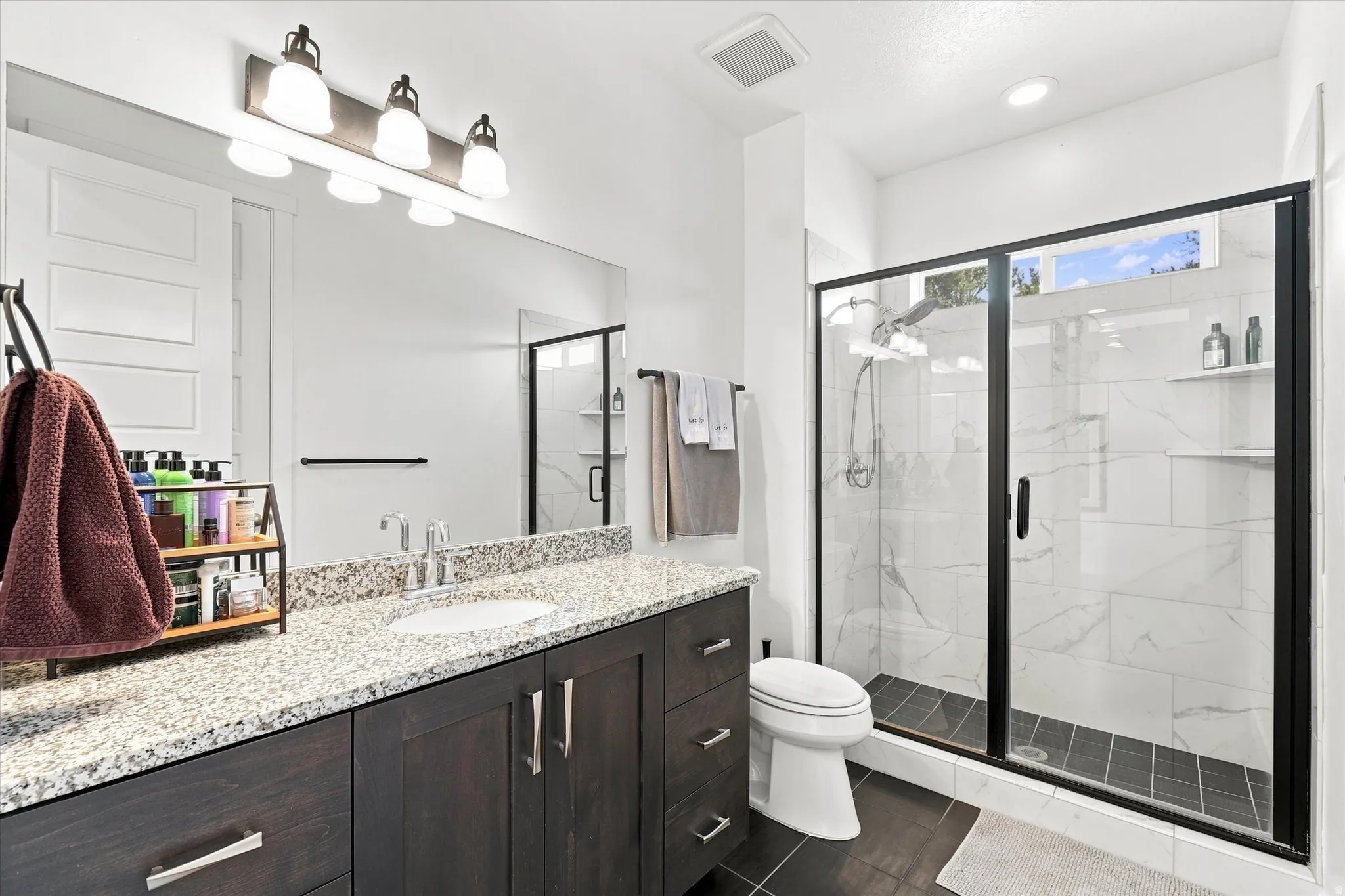 Bathroom featuring a dark wood-finish vanity with a granite countertop and undermount sink
