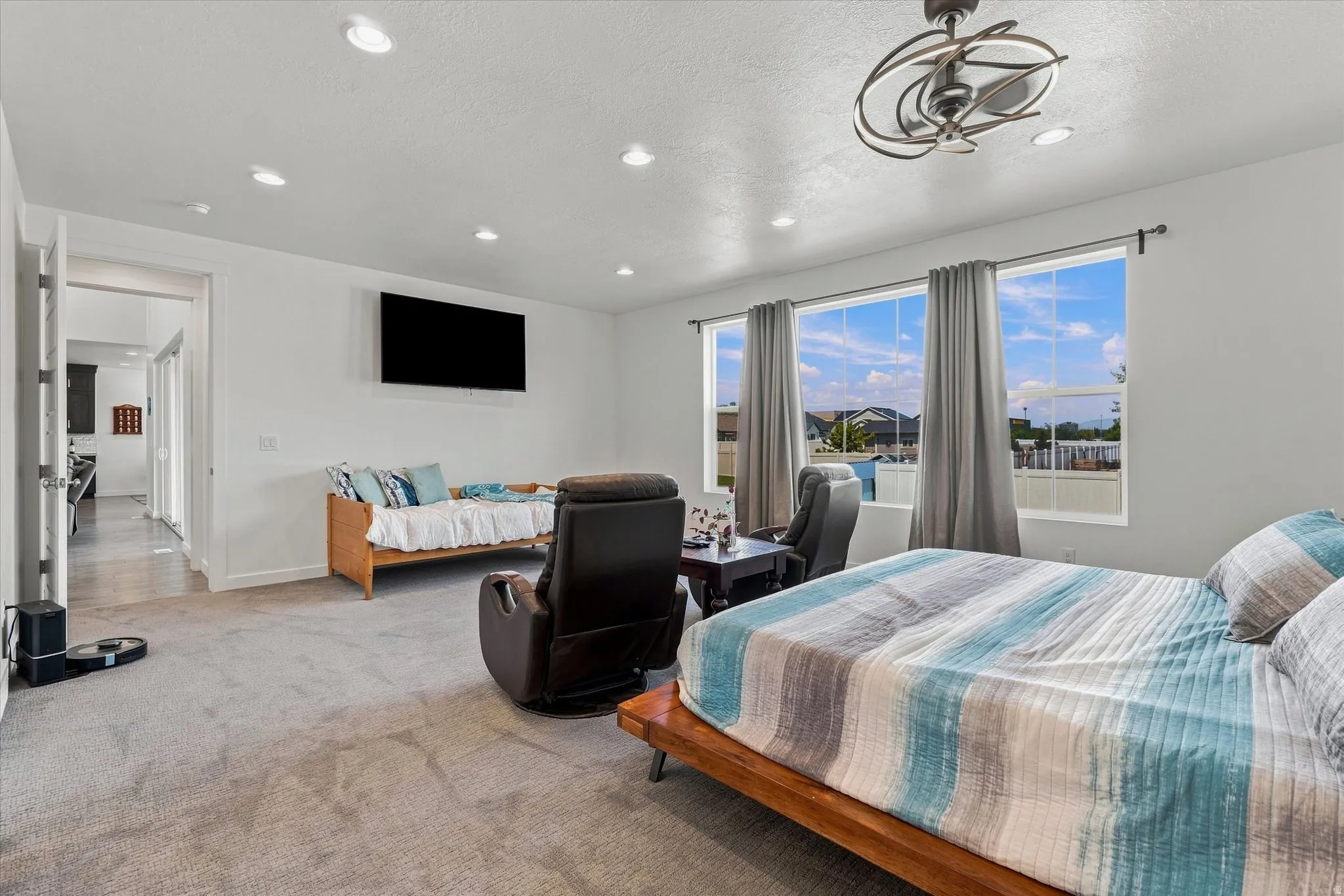 Spacious room featuring light gray carpeting, recessed lighting, and a modern ceiling fan