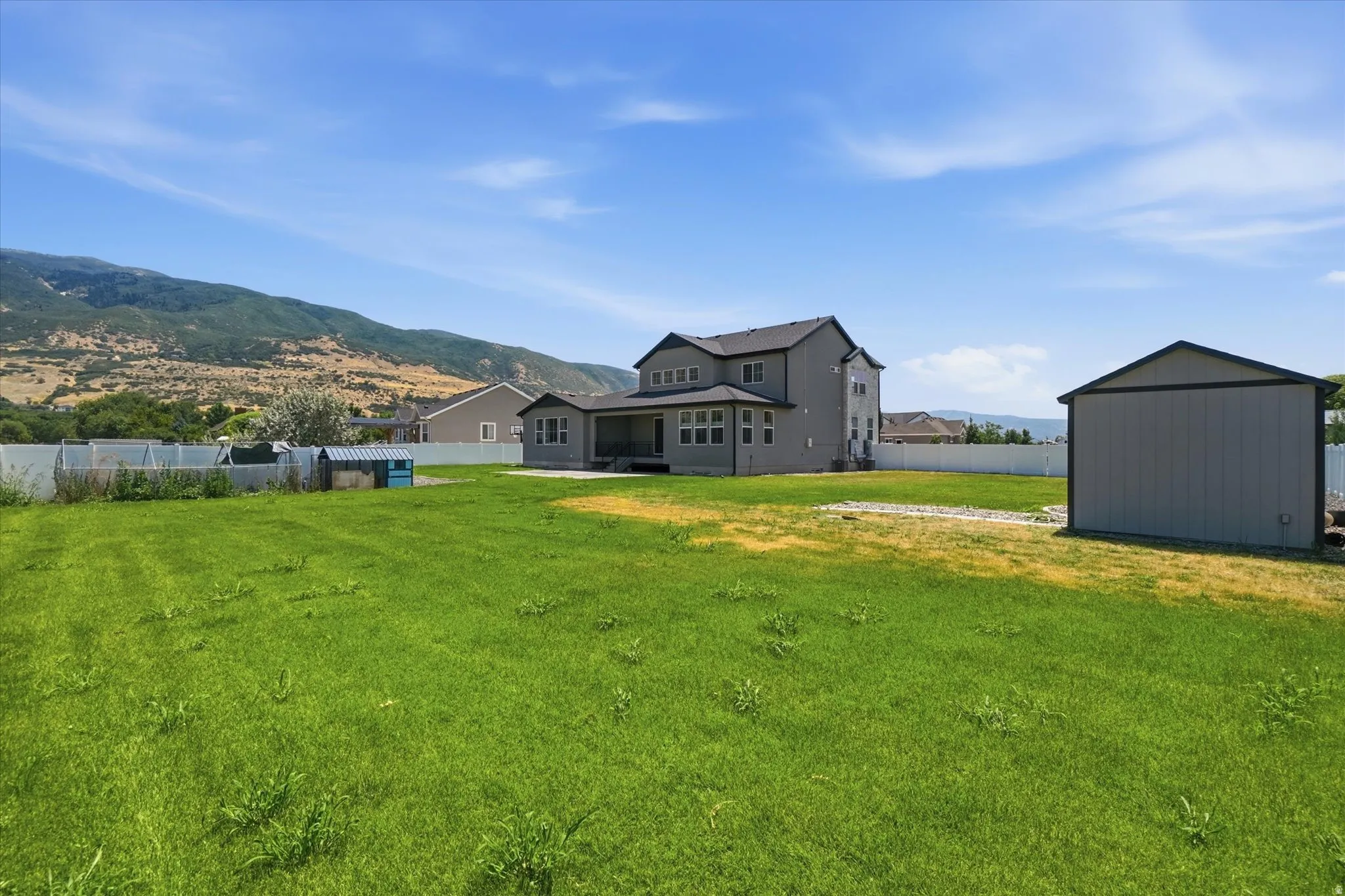 Expansive backyard featuring a large green space, a modern detached shed, and a privacy fence
