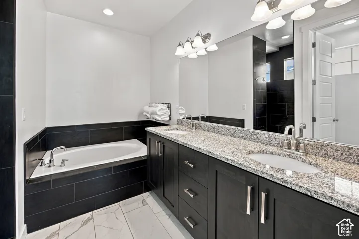 Primary Bedroom White-tiled flooring and dark tile accents complement the dual vanity with integrated sinks
