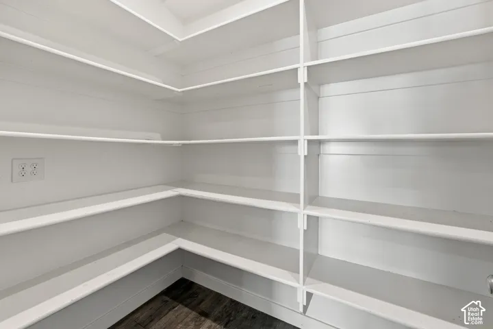 Expansive built-in pantry shelving with white finishes and wood-finish flooring