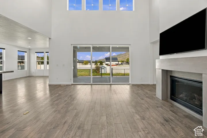 Expansive high ceilings with transom windows, engineered wood flooring, a built-in fireplace with a stone mantel, and a sliding glass door to covered deck
