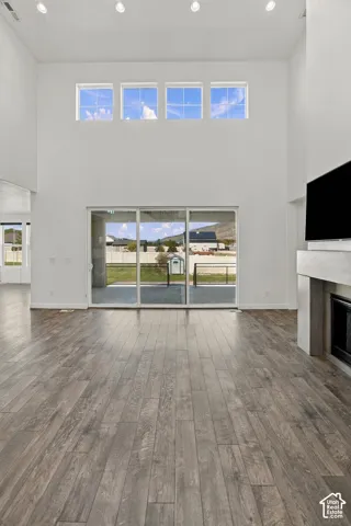 Vaulted ceiling with recessed lighting, engineered wood flooring, full-height windows, a built-in fireplace, and sliding glass doors