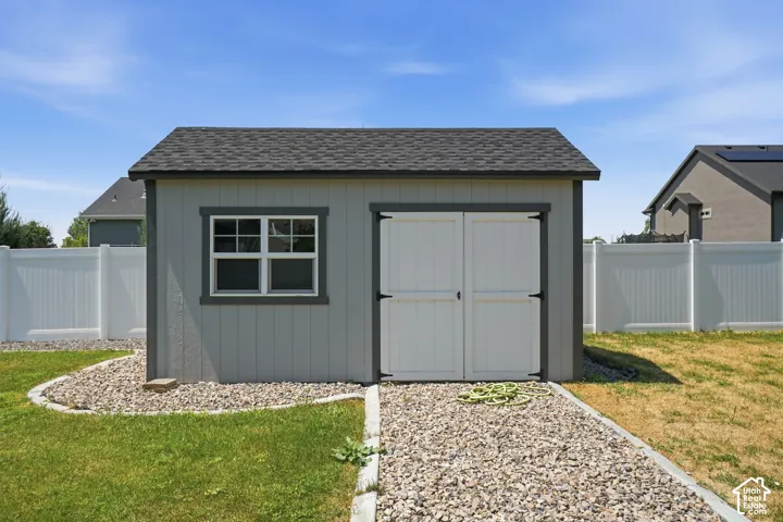 Storage shed place on concrete pad with electricity double entry doors, a multi-pane window, and an asphalt shingle roof