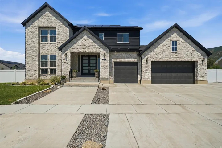 Modern two-story residence featuring light-toned stacked stone and dark siding