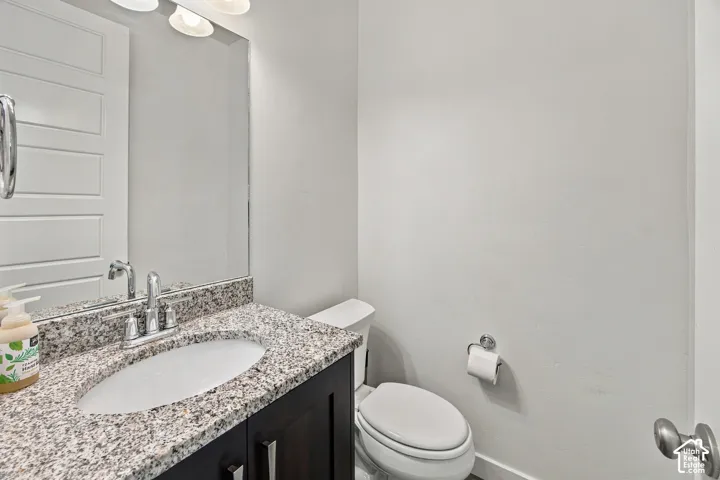 1/2 bath on main level. Vanity with granite countertop and undermount sink, chrome faucet, and dark wood-finish cabinetry