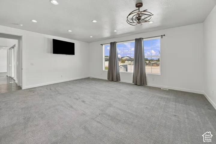 Primary ensuite bedroom with Recessed ceiling lighting, ceiling fan light fixture, two large windows, white walls, and gray carpeting