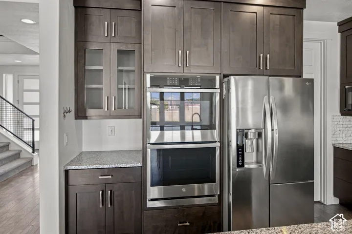 Dark wood-finish cabinetry with brushed nickel hardware, integrated stainless steel appliances, and light-toned countertop