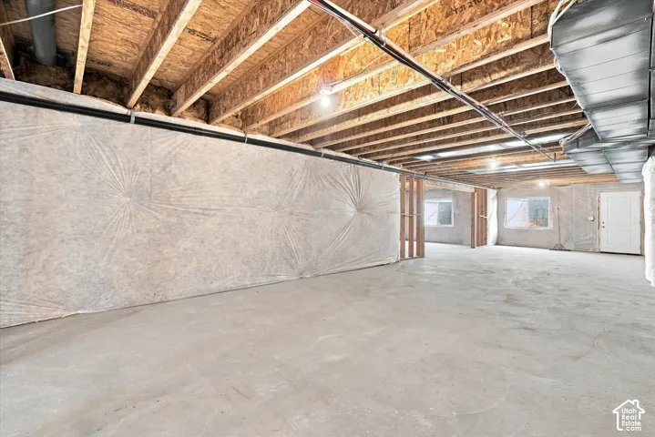 Unfinished basement with exposed ceiling joists and concrete flooring