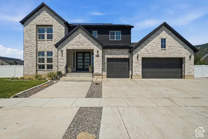 Modern two-story residence featuring light-toned stacked stone and dark siding