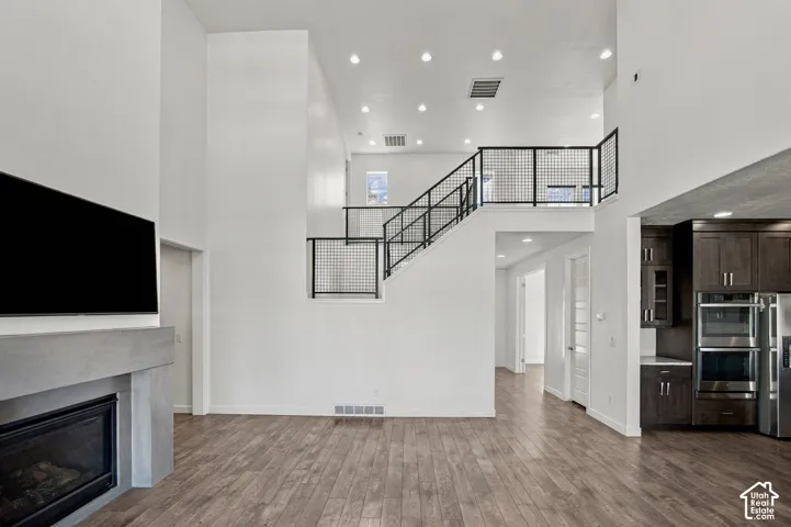 Open-concept living space with engineered wood flooring, a contemporary fireplace with a concrete-style mantle, and recessed lighting
