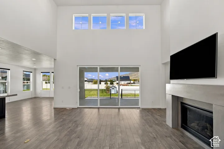 Expansive living space featuring engineered wood flooring, a contemporary fireplace with a stone surround, and high ceilings