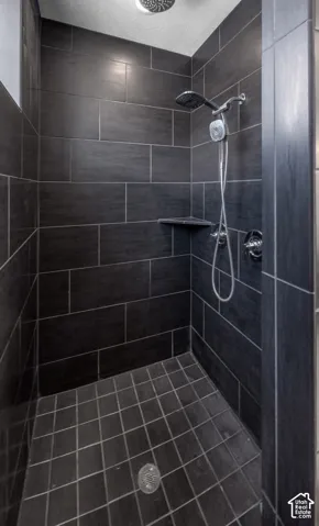 Primary Bedroom Walk-in shower with dark large-format wall tiles and complementary square floor tiles, featuring a corner shelf and a rain shower head