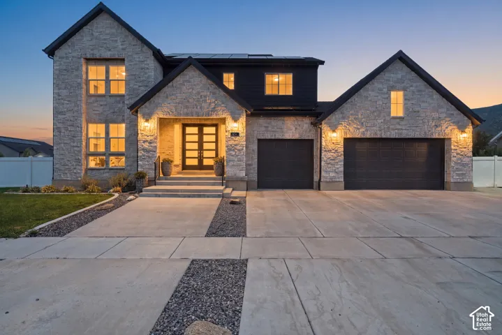 Stacked Stone exterior with a prominent entry, dual garage doors, and solar panels