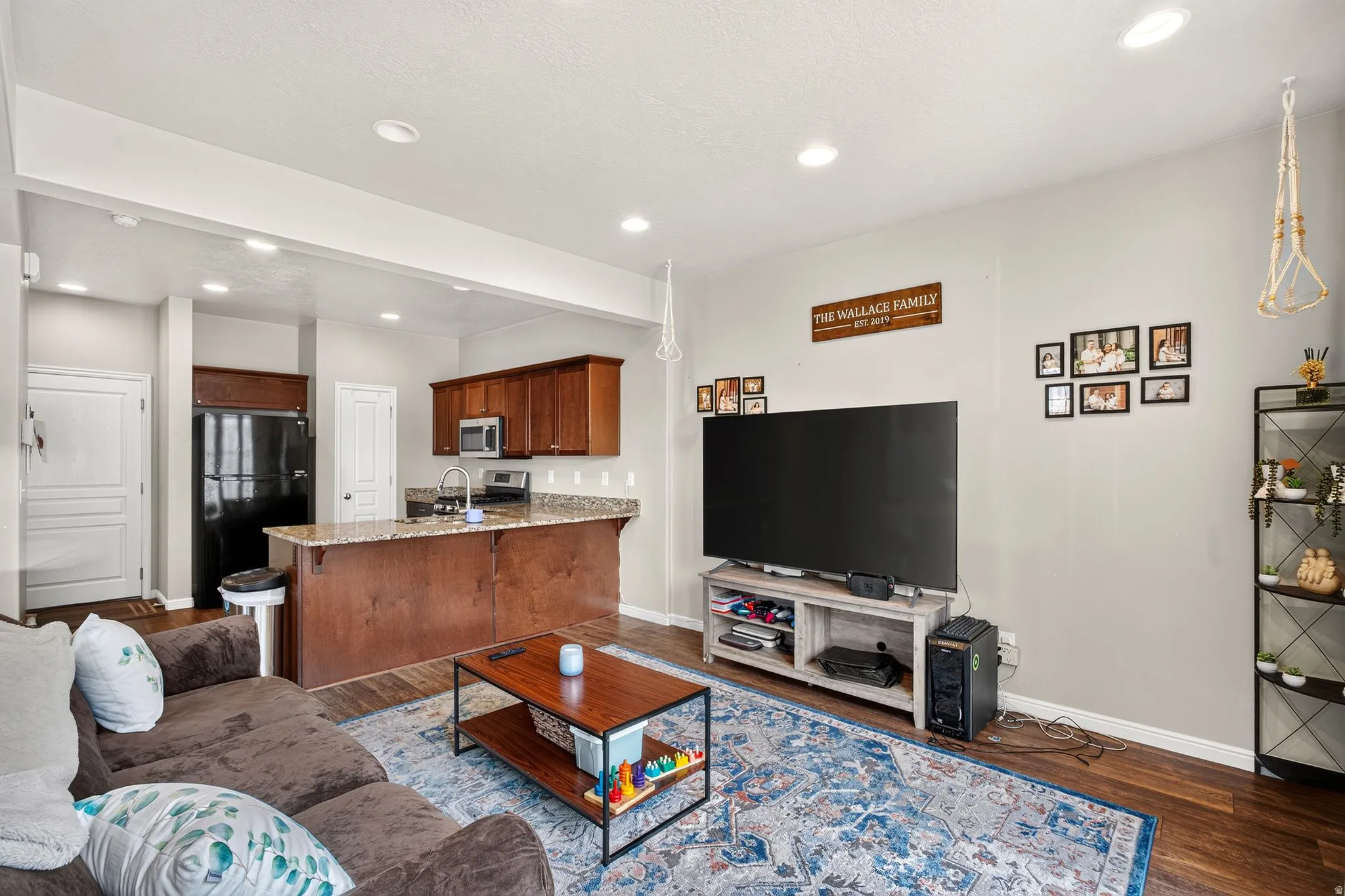 Open concept living area featuring dark wood-finish flooring, recessed lighting, and a kitchen with wood cabinetry and a light-toned countertop