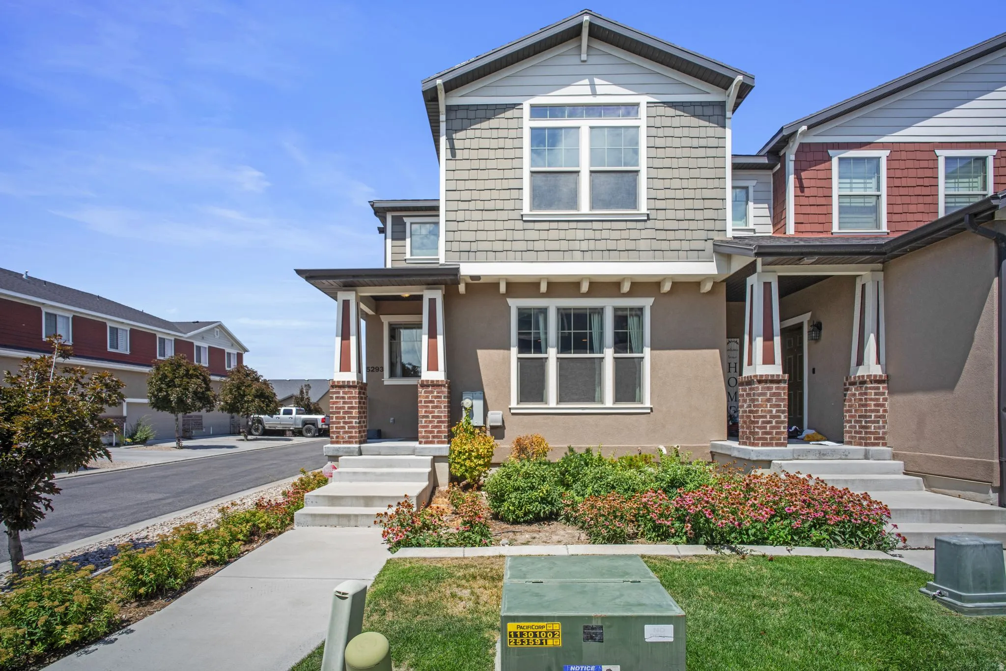 Multi-story townhome with a covered entryway featuring brick columns and decorative trim