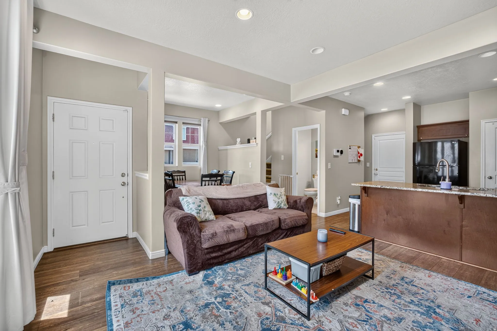 Open-concept living area featuring wood-finish flooring, recessed lighting, and a neutral wall palette