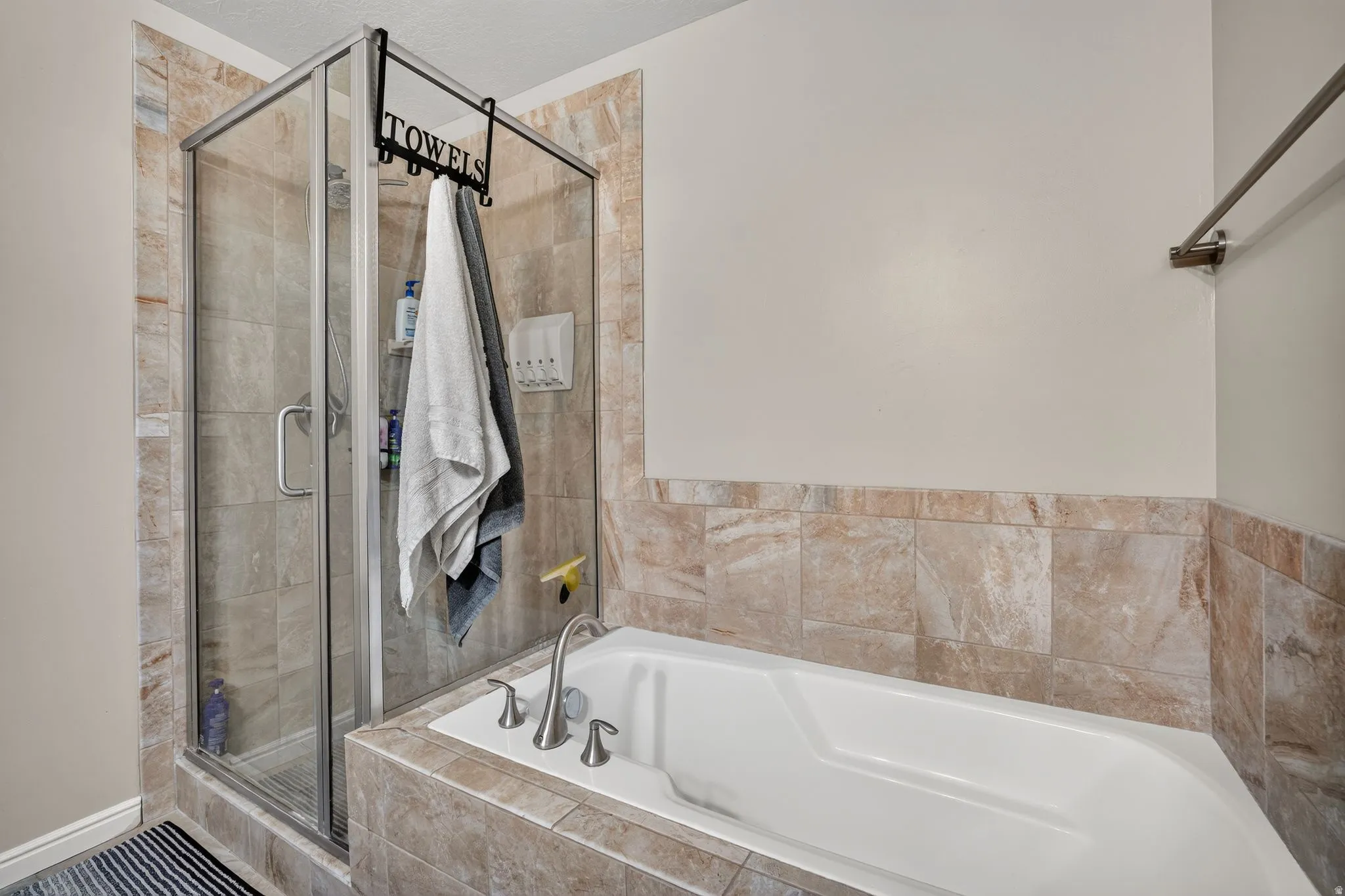 Built-in corner soaking tub with deck-mounted brushed nickel fixtures, surrounded by large format natural-toned tile