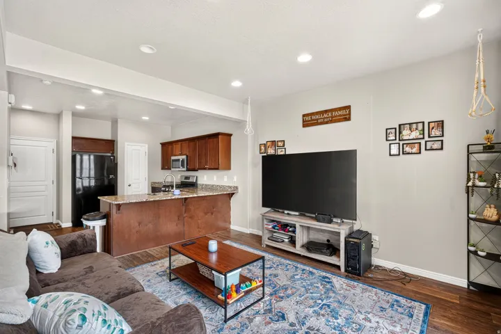Open concept living area featuring dark wood-finish flooring, recessed lighting, and a kitchen with wood cabinetry and a light-toned countertop