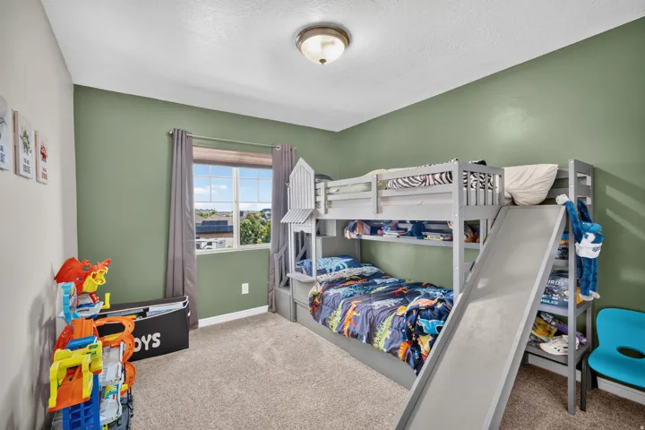 Carpeted room featuring light green walls and a single window with a roller shade