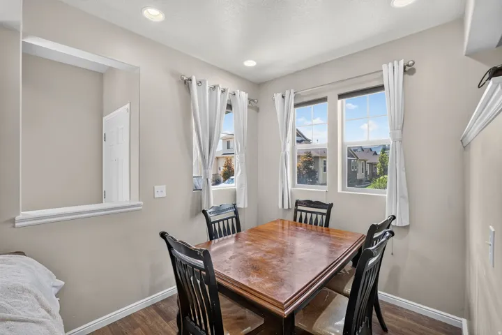 Dining area featuring recessed lighting, a pass-through window with trim, two windows, and wood-finish flooring