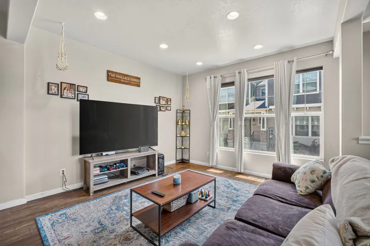 Spacious living area featuring three large windows, recessed ceiling lighting, and wood-finish flooring