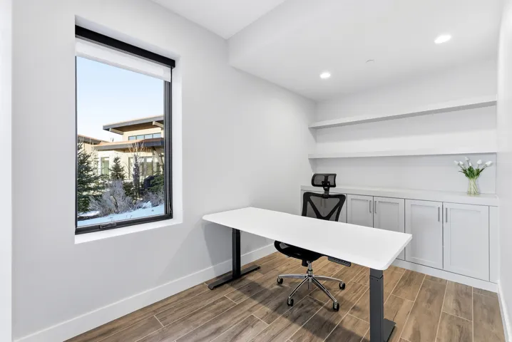 Bright room featuring wood-finish flooring, built-in cabinetry, floating shelves, recessed lighting, and a large window with exterior views