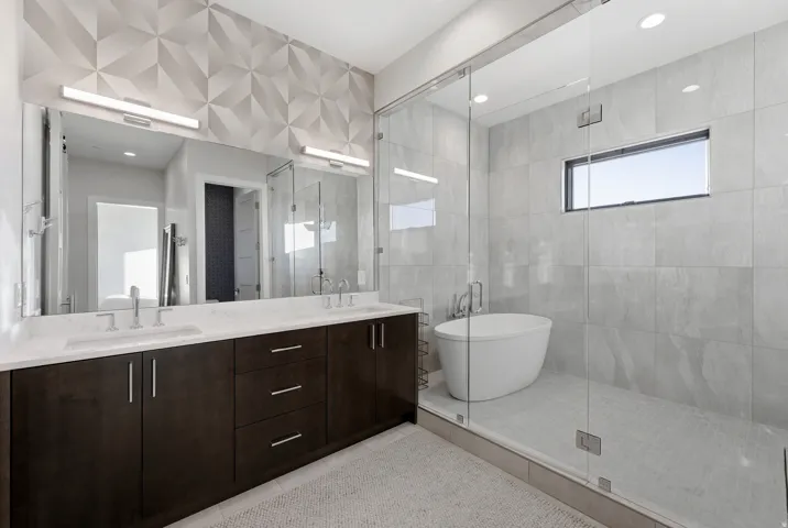Dual vanity with white undermount sinks, stone countertops, and brushed nickel fixtures