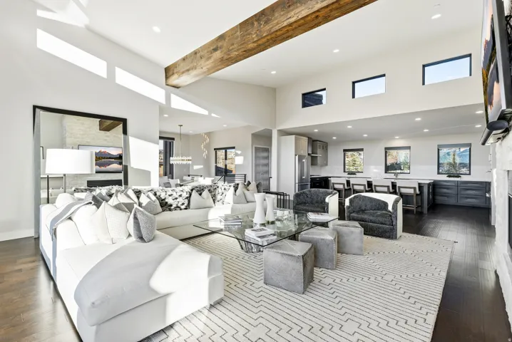 Spacious open-concept living area featuring a vaulted ceiling with a visible wooden beam