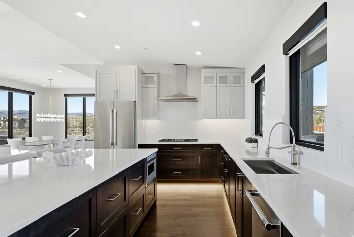 Modern kitchen featuring a large island with integrated microwave, stainless steel appliances, white quartz countertops, and dark wood-finish cabinetry