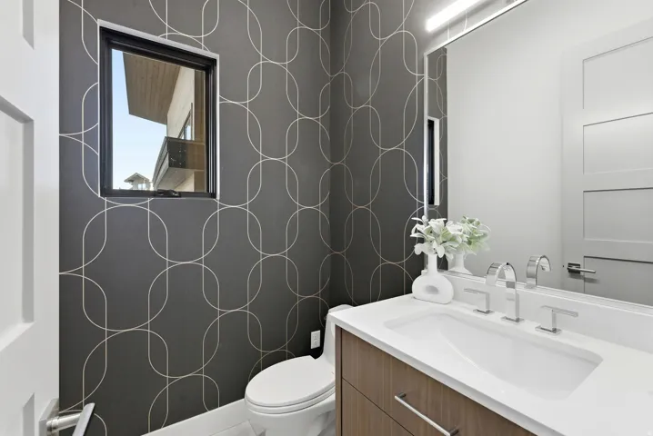 Modern powder room featuring a wood-finish vanity with an integrated rectangular sink, chrome faucet, and a large wall-mounted mirror