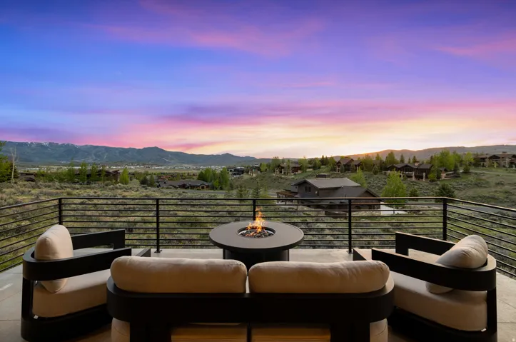 Expansive outdoor deck featuring a modern fire pit, concrete flooring, and horizontal metal railing