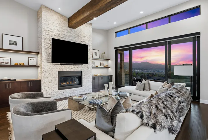 Living area featuring a floor-to-ceiling stacked stone fireplace, a dark wood beam, and built-in shelving