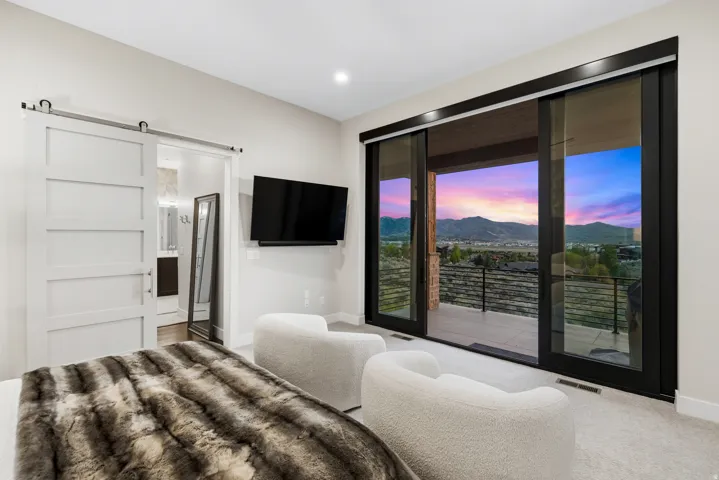 Expansive sliding glass doors open to a private balcony with a mountain backdrop