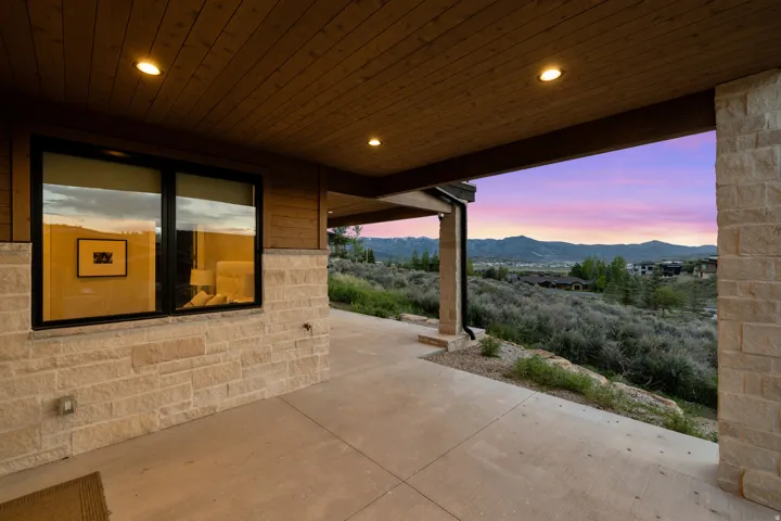 Covered patio with a concrete surface, stone veneer siding, wood-finish ceiling with recessed lighting, and expansive mountain scenery