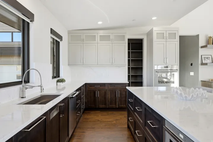 Spacious kitchen featuring dark wood-finish lower cabinetry, white upper cabinetry with frosted glass inserts, and light-toned countertops