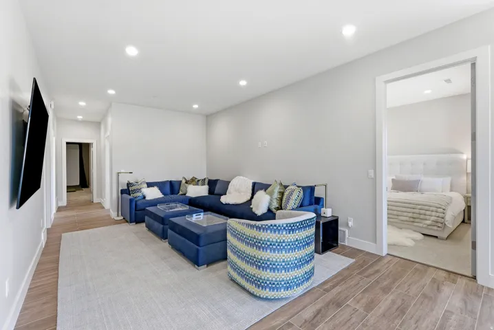 Open-concept living space with recessed lighting, light gray walls, and wood-finish flooring