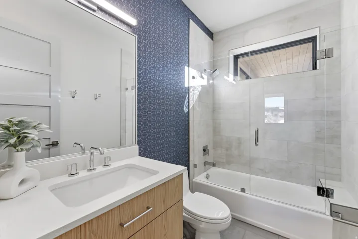 Bathroom with a light wood-finish vanity, white countertop, and integrated sink