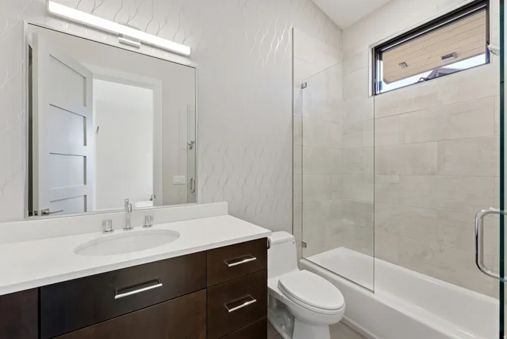 Contemporary bathroom featuring a dark wood-finish vanity with chrome hardware, an undermount sink, and a white countertop