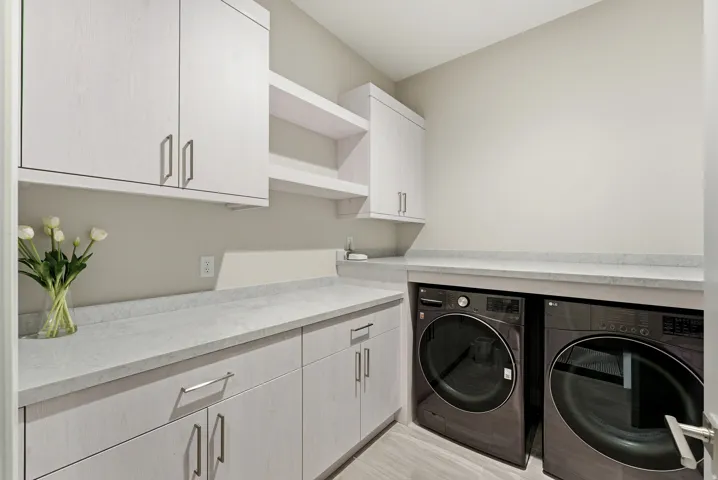 Dedicated utility room featuring light wood-finish cabinetry, light-toned countertops, and built-in front-load appliances
