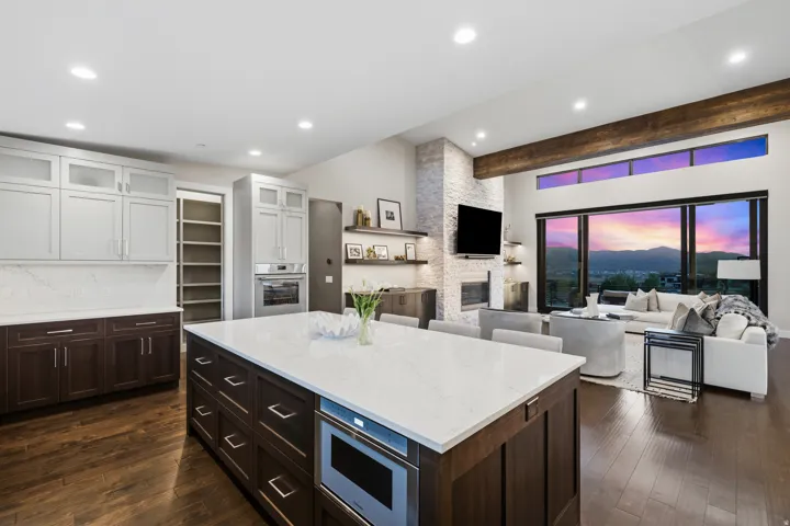 Expansive kitchen and living area featuring a large center island, built-in stainless steel microwave, integrated wall oven, and recessed lighting