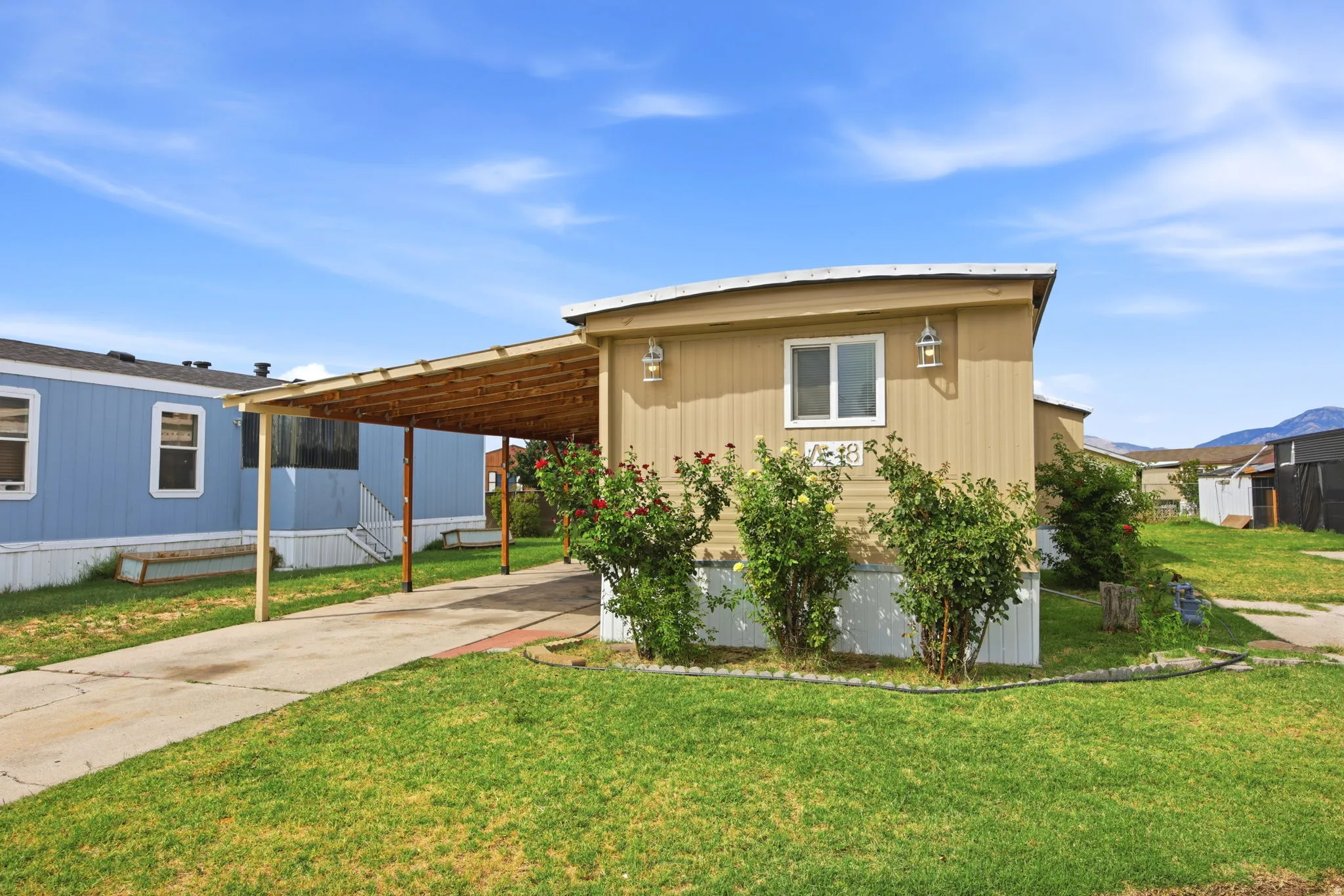 Exterior featuring tan siding, white trim, and a covered carport