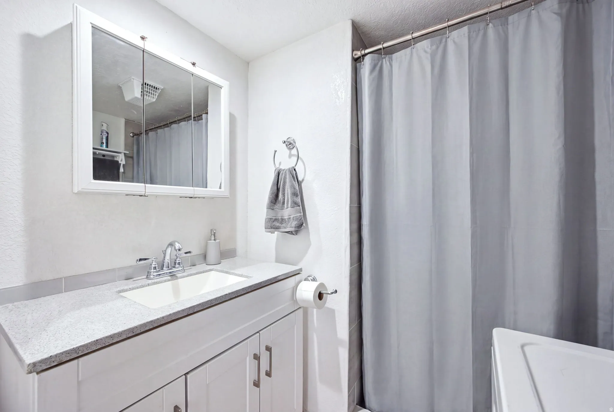 Bathroom featuring a white vanity with a light-colored countertop, an undermount sink, and a chrome faucet