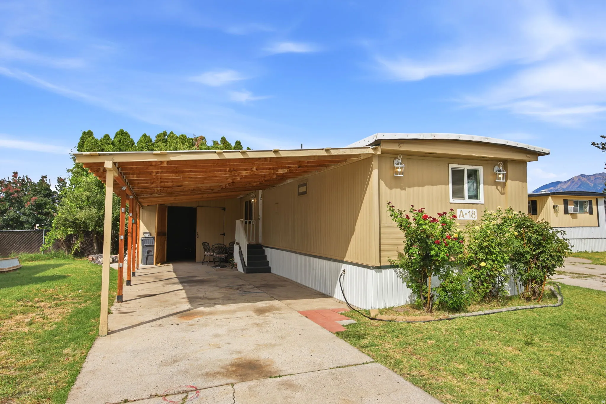Single-story residence featuring a covered carport, concrete driveway, and a tan siding exterior