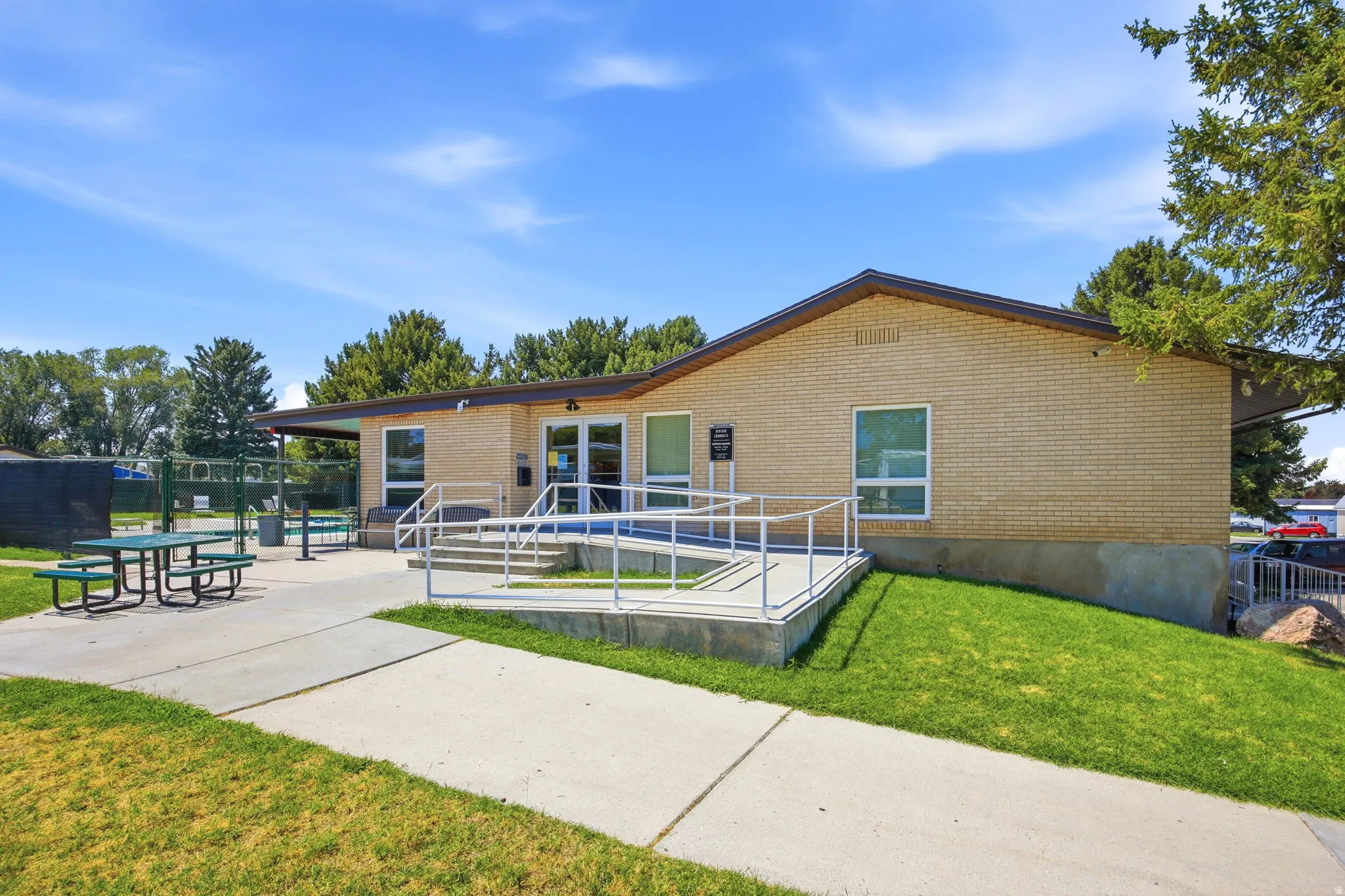 Brick exterior building with a prominent entrance featuring a ramp and stairs with metal railings