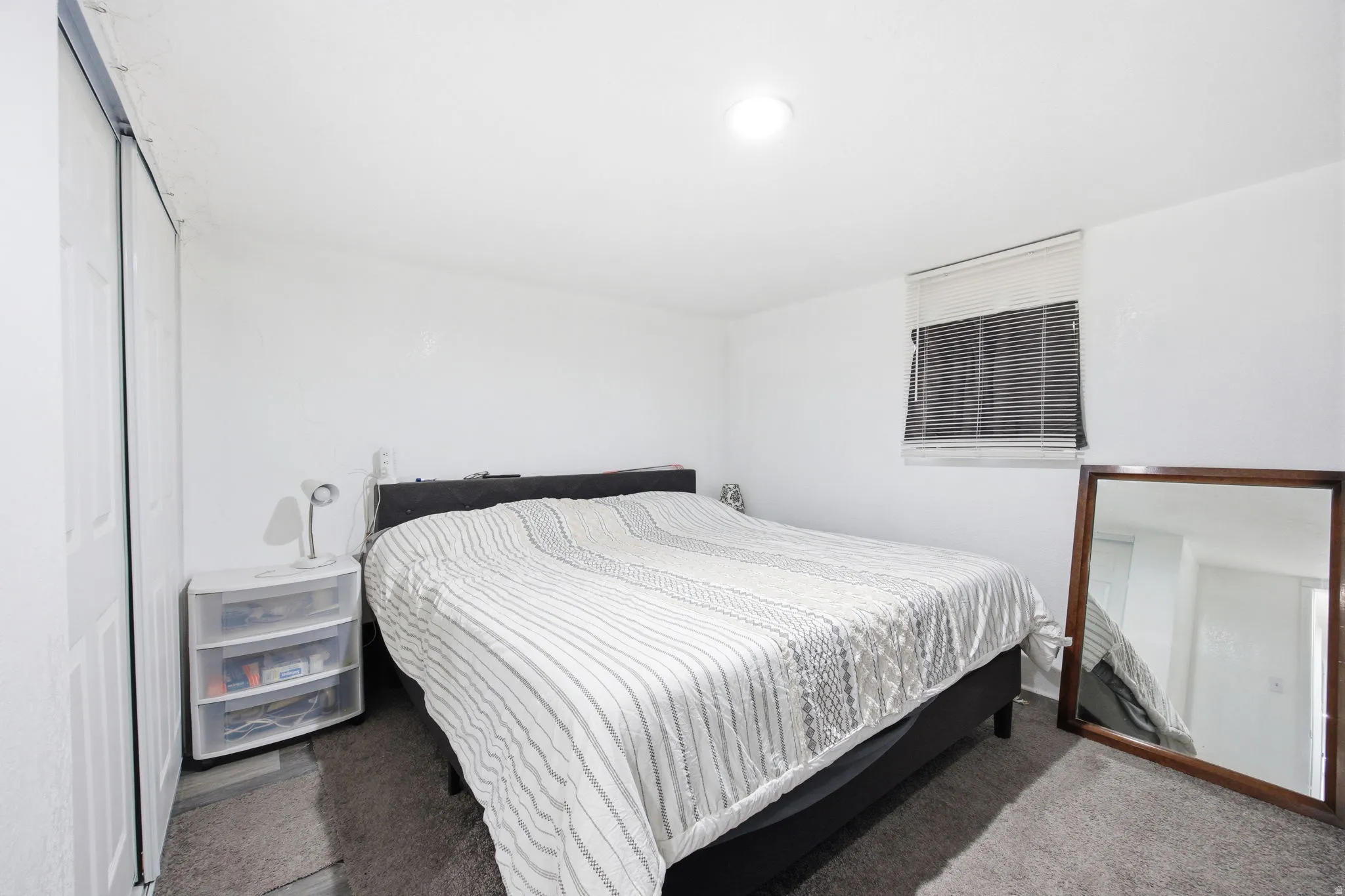 Bedroom featuring a window with horizontal blinds, overhead lighting, and wall-to-wall carpeting