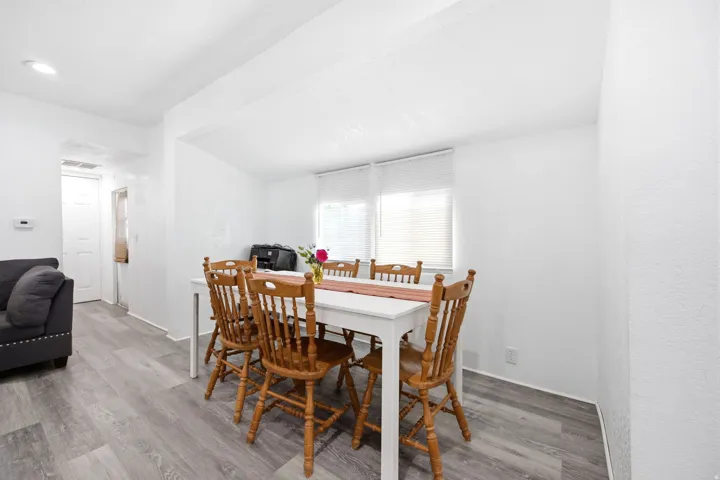 Open-concept living area featuring light gray wood-finish flooring, recessed lighting, and white textured walls