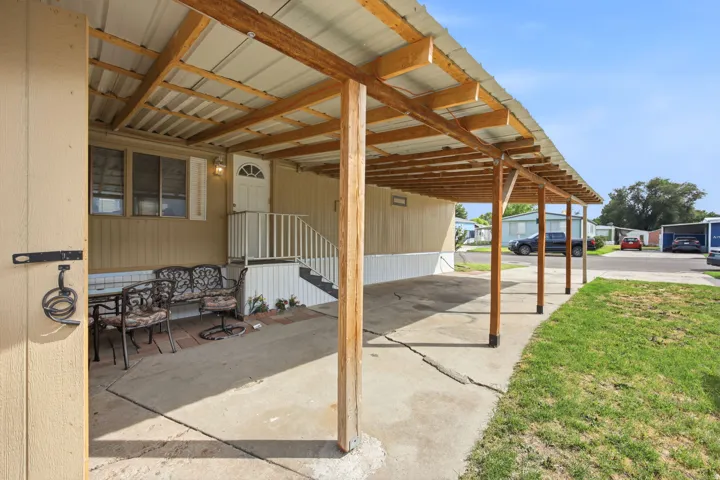 Exterior featuring a covered carport, concrete driveway, and a covered porch area with a white entry door and railing
