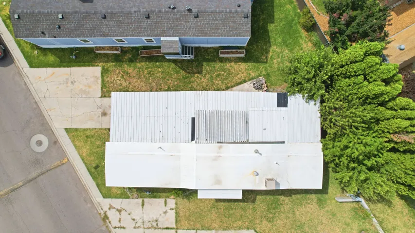 Single-story property with a light-colored roof and surrounding green space